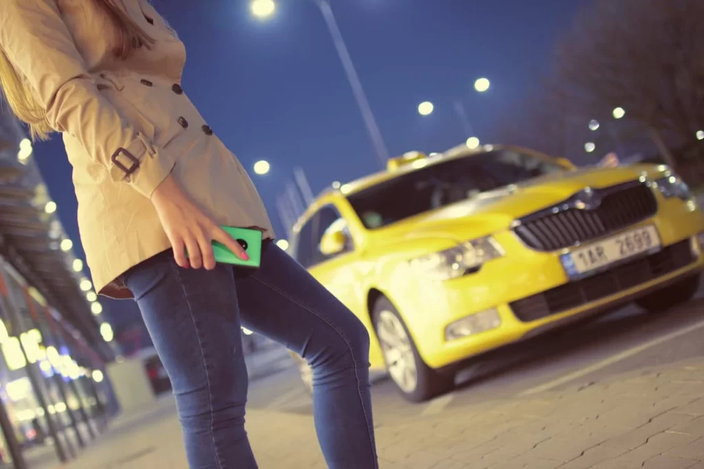 Foto perempuan memegang ponsel dengan mobil di latar belakangnya. Gambar ini merupakan contoh be bold, be italic pada brand Gojek.